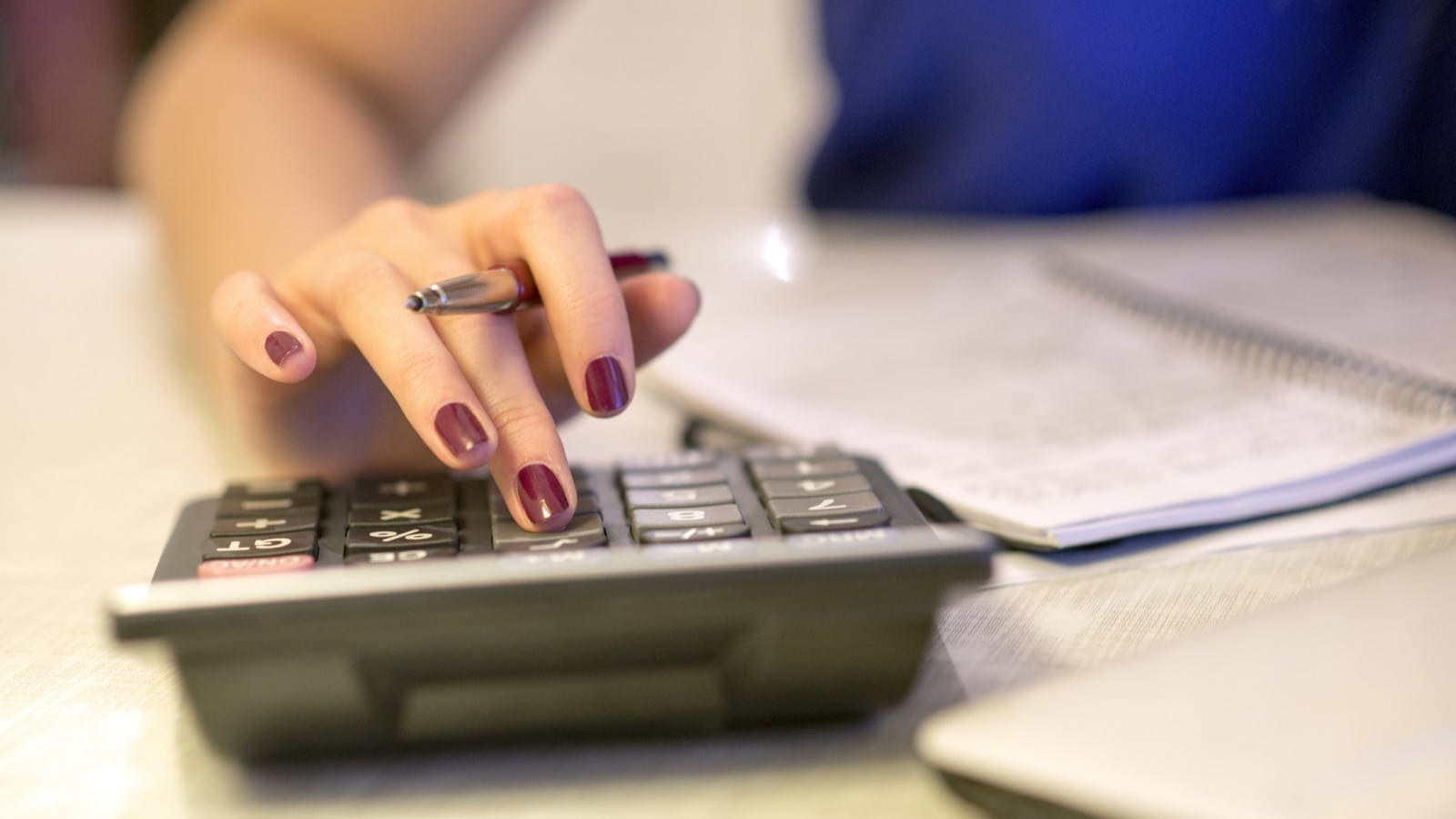Woman Using A Calculator At Her Desk Stock Photo