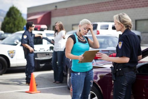 A woman talking to the police after a car accident.