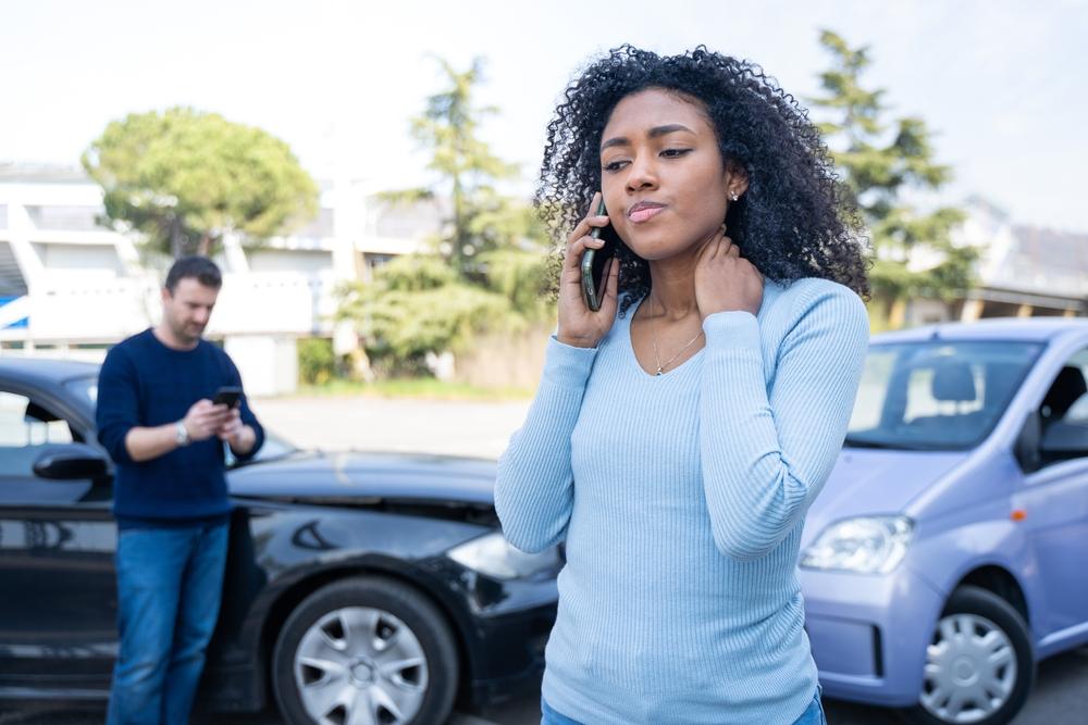 A woman on her phone after a collision, wondering if car accident settlements are taxable in Colorado.