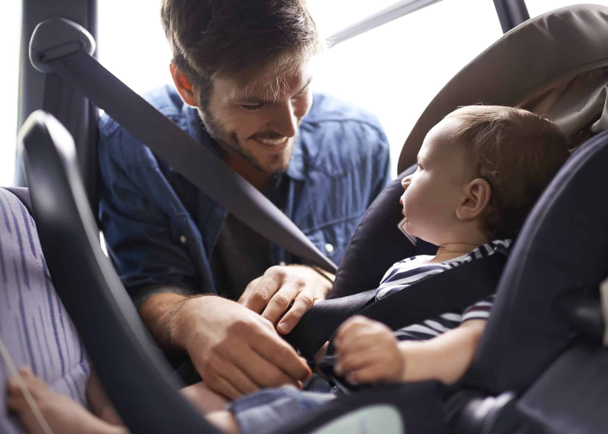 Small Child Being Fastened Into Car Seat By Father Stock Photo